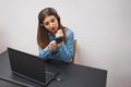 Young woman doing make up while sitting at the laptop.