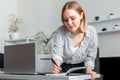 Young woman doing paper work in office Standing near laptop During working day In bright home office interior. Student Royalty Free Stock Photo