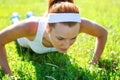 Young woman doing push ups on green Royalty Free Stock Photo