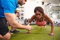 Young woman doing push ups under supervision of a trainer Royalty Free Stock Photo