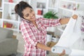 Young woman doing repairs in apartment wallpapering on wall