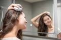 Young woman doing self hair scalp massage with scalp massager or hair brush for hair growth stimulating at home bathroom Royalty Free Stock Photo