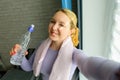 Young woman doing selfies after workout. Smiling attractive fitness girl with towel and bottle of water after training. Sport at Royalty Free Stock Photo