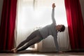 Young woman doing side plank pose at home.