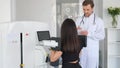 A young woman is doing a spinal examination in a diagnostic machine with a physiotherapist.