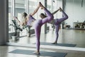 Young woman doing stretching exercise by mirror on floor mat in bright yoga class room Royalty Free Stock Photo