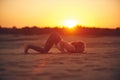 Young woman is doing yoga asana Ashtanga Namaskarasana - eight limbed salutation pose in the desert at sunset