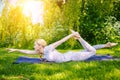 young woman doing yoga asana in park. girl stretching exercise in yoga position. happy and healthy woman sitting in Royalty Free Stock Photo
