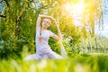 young woman doing yoga asana in park. girl stretching exercise in yoga position. happy and healthy woman sitting in Royalty Free Stock Photo