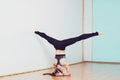 Young woman doing yoga asana upavishtha konasana shirshasana in studio. Bound Angle Pose in Head Stand.