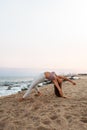 Young woman doing yoga at the beach. Female practices the wild thing yoga pose at sunset. Copy space. Vertical image.