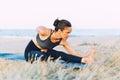 Young woman doing yoga exercise on the ground outdoors by the sea