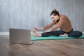 Young woman doing yoga exercise at home watching online yogs class at laptop Royalty Free Stock Photo