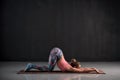 Young woman doing yoga exercise Uttana shishosana or extended puppy pose