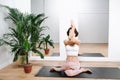 Young woman doing yoga at home. Sitting in a cow pose with intertwined hands Royalty Free Stock Photo