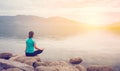 Young woman doing yoga in Lotus pose in the mountain and sunrise background