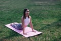 Young woman is doing yoga in park. Attractive woman in sports clothes lies on pink exercise mat in Cobra pose