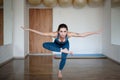 Young woman doing yoga, pilases indoors, standing in one-legged chair pose, Utkatasana. Royalty Free Stock Photo