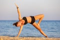 Young woman doing yoga side plank pose or vasistasana at the beach Royalty Free Stock Photo