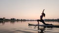 Young woman doing yoga on SUP board at sunset. Slow motion futage