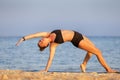 Young woman doing yoga wild thing pose or camatkarasana at the beach Royalty Free Stock Photo