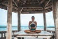 Young woman doing yoga in the wooden gazebo at the beach