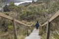 A young woman down at wooden stairs into trekking path inside Chingaza National Nature park with mountain and lake landscape