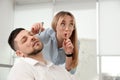 Young woman drawing on colleague`s face while he sleeping in office. Funny joke Royalty Free Stock Photo