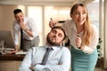 Young woman drawing on colleague`s face while he sleeping in office. Funny joke Royalty Free Stock Photo