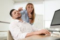 Young woman drawing on colleague`s face while he sleeping in office. Funny joke Royalty Free Stock Photo