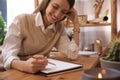 Young woman drawing in sketchbook with pencil at wooden table indoors, focus on hand Royalty Free Stock Photo