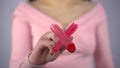 A young woman draws a red cross on the glass. A girl in a pink sweater draws with a brush and paint. Close-up.