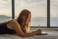 Young woman draws on a tablet against the background of a window with a sea view. Designer, sketching Royalty Free Stock Photo