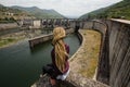 Young woman with dreadlocks sitting near a power plant in the mountains. Royalty Free Stock Photo