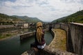 Young woman with dreadlocks sitting near a power plant in the mountains. Royalty Free Stock Photo