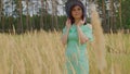 Young woman in dress and hat standing in wheat field. Pretty lady poses, standing in ears of wheat. Royalty Free Stock Photo