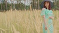 Young woman in dress and hat standing in wheat field. Pretty lady poses, standing in ears of wheat. Royalty Free Stock Photo