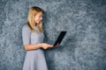 Young woman in dress with laptop over gray background Royalty Free Stock Photo