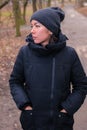 Young woman dressed in modern black winter clothes, coat and knit cap is walking in the park Royalty Free Stock Photo