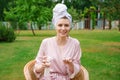 Young woman dressed for shower towel wrapped head for hair hold in bottles Royalty Free Stock Photo