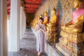 Young woman dressed in Thai dress with accessories holds a welcome ceremony at Wat Arun where many Buddha statues are row. It is a