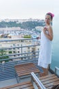 Young woman dressed in towel standing on balcony