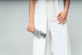 Young woman dressed in white holding in hands microphone isolated on a grey studio background Royalty Free Stock Photo