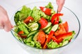 Young woman dressing vegetable salad with olive oil on a white background Royalty Free Stock Photo