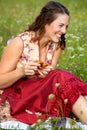 Young woman in drindl sitting in a meadow and laughing Royalty Free Stock Photo