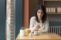 Young woman drink coffee and use smartphone at cafe