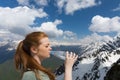 Young woman drink water from plastic bottle in the mountains on the snow peaks background Royalty Free Stock Photo