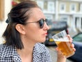 Young woman is drinking beer in a cafe or restaurant pub outdoor. Drinking alcohol. Candid. Refreshment, summer time Royalty Free Stock Photo