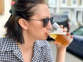 Young woman is drinking beer in a cafe or restaurant pub outdoor. Drinking alcohol. Candid. Refreshment, summer time Royalty Free Stock Photo