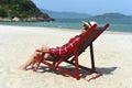 Young woman drinking beer and sitting on deck chair at beach in Nha Trang Royalty Free Stock Photo